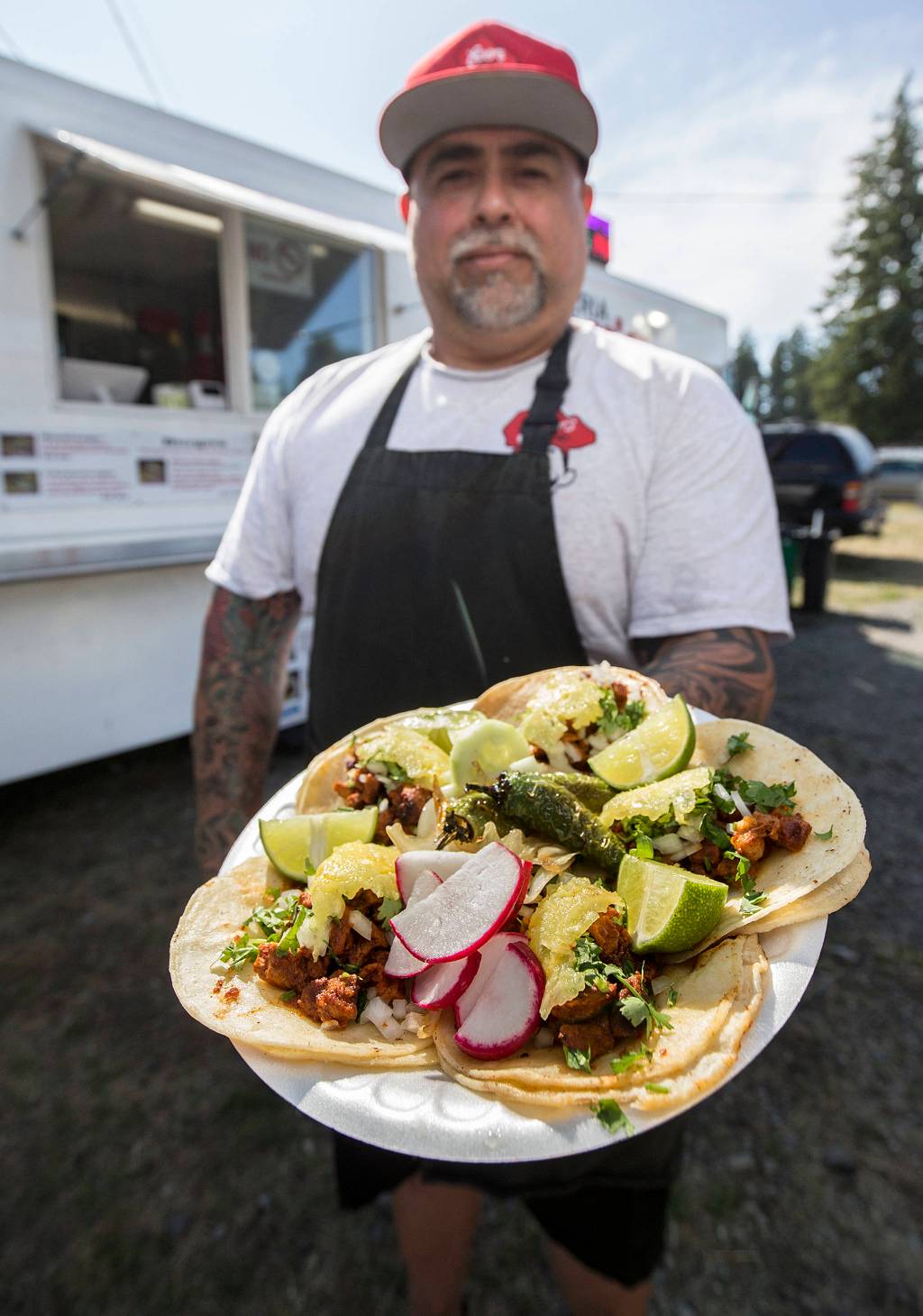 Everardo Ever Garcia displays his signature al pastor tacos  made with marinated pork, onion, cilantro and pineapple  on Aug. 5 in Everett. (Andy Bronson / The Herald )