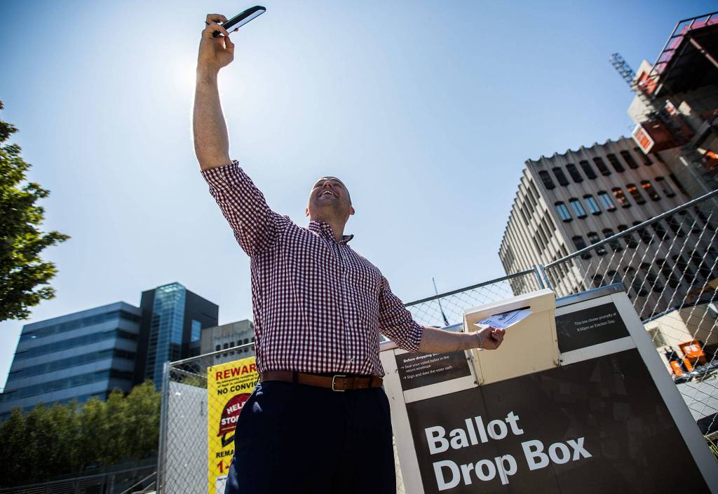 Snohomish County Council District 2 candidate Alex Lark stops to take a photo before dropping his ballot in the box on the Snohomish County Campus Plaza on Aug. 6 in Everett. (Olivia Vanni / The Herald)