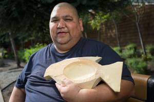 Tulalip carver Steven Madison holds a flounder bowl made of yellow cedar, which, once finished, will be auctioned off at a fundraising event for the Hibulb Cultural Center. (Andy Bronson / The Herald)