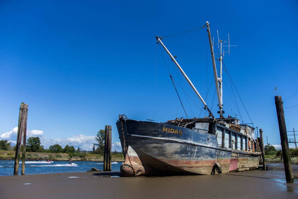 People on jet skis and boats drive past the Hannah Marie, formerly called the Midas, that was run aground along the banks of the Snohomish River, on July 3, 2018, in Everett. (Olivia Vanni / Herald file)