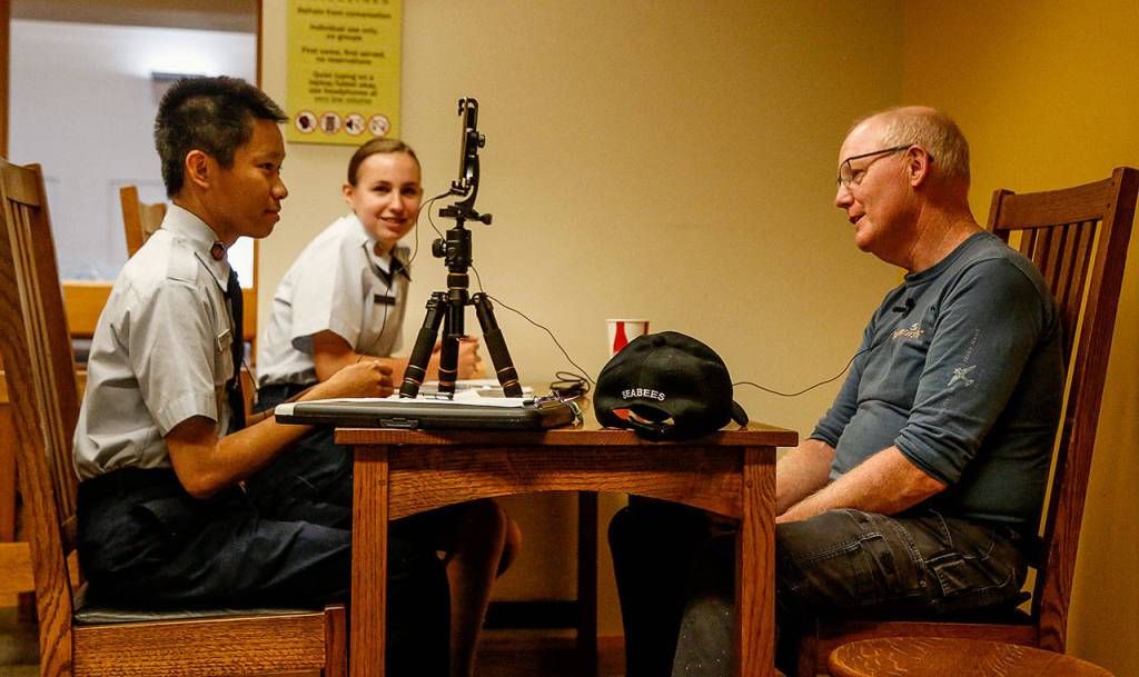 Jay Bonner tells interviewers Randolph Halim, 15, (left) and Karolina Dubiel, 14, about his duty with the Seabees, which took him to the Camp David Presidential retreat for two years. (Dan Bates / The Herald)