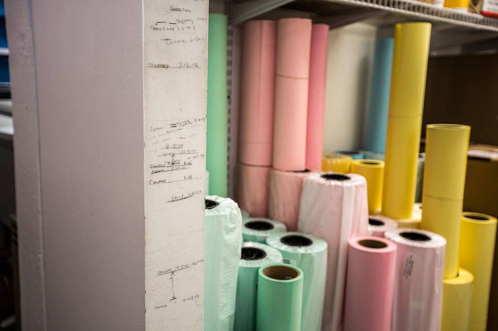 Different height measurements of family members and friends mark the wall at Bills Blueprints in Everett. (Olivia Vanni / The Herald)