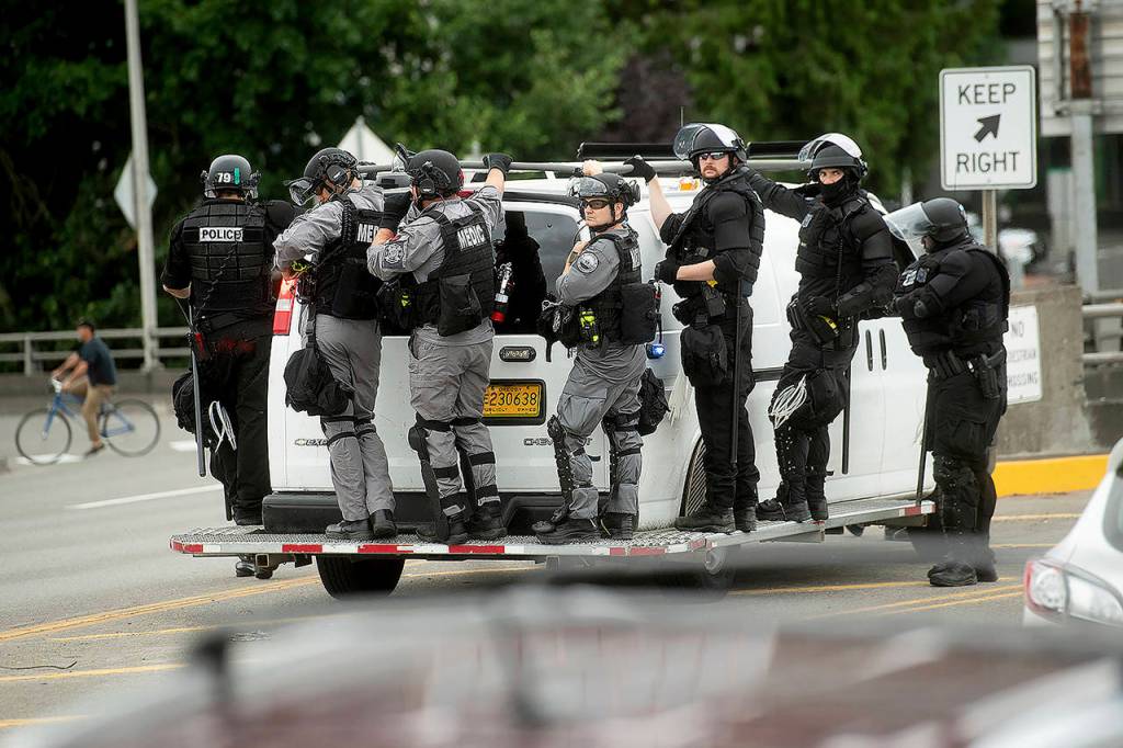 Police officers ride on the side of a van as right-wing demonstrators and counter-protesters gather in Portland for an End Domestic Terrorism rally on Saturday. Police seized metal poles, bear spray and other weapons as hundreds of far-right protesters and anti-fascist counter-demonstrators swarmed downtown Portland. (AP Photo/Noah Berger)