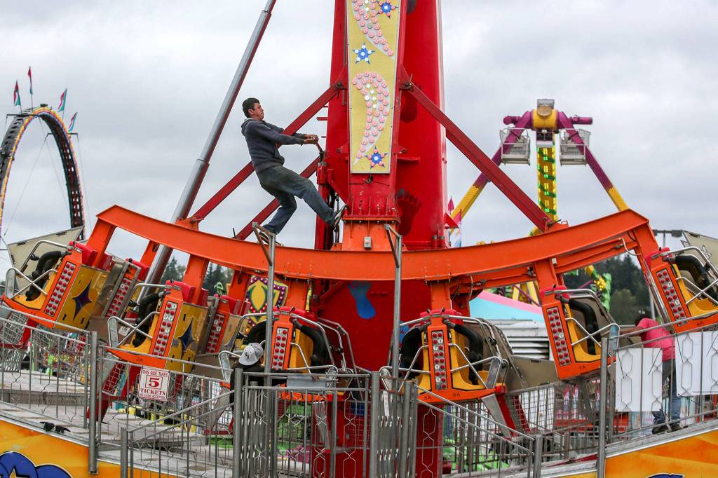 A crew member works to setup a ride Wednesday afternoon at the Evergreen State Fairgrounds in Monroe on August 21, 2019. (Kevin Clark / The Herald)
