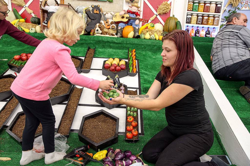 Zoe Hart handles off vegetables to her mom Nicole Hart Wednesday afternoon at the Evergreen State Fairgrounds in Monroe on August 21, 2019. (Kevin Clark / The Herald)