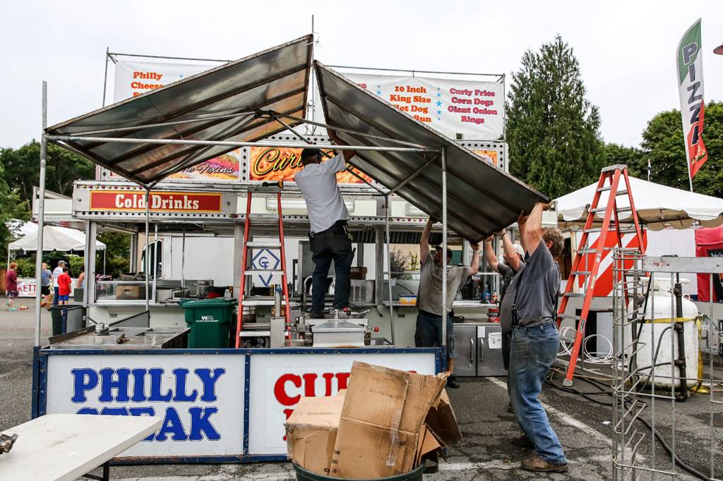 Crews work to assemble a food stall Wednesday afternoon at the Evergreen State Fairgrounds in Monroe on August 21, 2019. (Kevin Clark / The Herald)