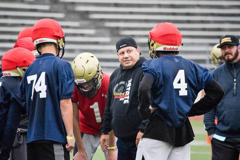 Everett head coach Brien Elliott talks to his players between plays at Everett Memorial Stadium on Wednesday, Aug. 21. (Katie Webber / The Herald)