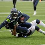 Seahawks wide receiver DK Metcalf (14) is tackled by Broncos cornerback Chris Harris after making a catch during the first half of a preseason game on Aug. 8, 2019, in Seattle. (AP Photo/Elaine Thompson)