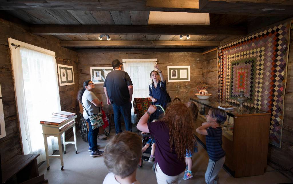 Michelle Crapo points out parts of the Shannahan Cabin to her kids and their cousins on opening day of the Evergreen State Fair on Thursday, Aug. 22, 2019 in Monroe, Wash. The cabin is the first building to be placed on the Snohomish County Register of Historic Places. (Andy Bronson / The Herald)