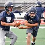 Sultan senior quarterback Willy Bennett fakes a hand-off to senior running back Aidan Fleming during practice on Aug. 23, 2019, at Sultan High School. (Katie Webber / The Herald)