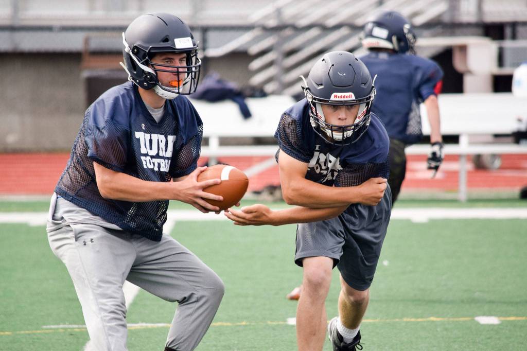 Sultan senior quarterback Willy Bennett fakes a hand-off to senior running back Aidan Fleming during practice on Aug. 23, 2019, at Sultan High School. (Katie Webber / The Herald)