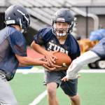 Sultan senior quarterback Willy Bennett hands the ball off to senior running back Aidan Fleming during practice on Aug. 23, 2019, at Sultan High School. (Katie Webber / The Herald)