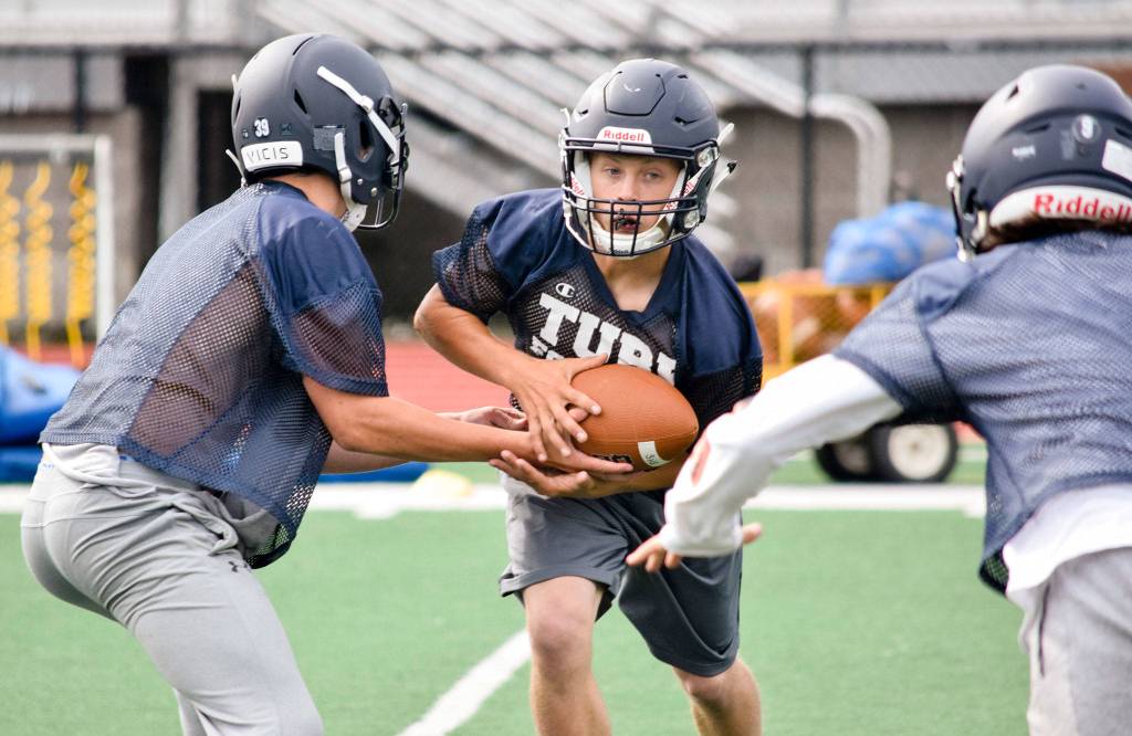 Sultan senior quarterback Willy Bennett hands the ball off to senior running back Aidan Fleming during practice on Aug. 23, 2019, at Sultan High School. (Katie Webber / The Herald)