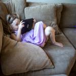 <a href="https://www.heraldnet.com/life/fundraiser-to-help-4-year-old-marysville-girl-fighting-cancer/" target="_blank">Sadie Sheldon</a> hides behind her iPad as she watches YouTube Kids at her home on Aug. 15 in Marysville. (Olivia Vanni / The Herald)