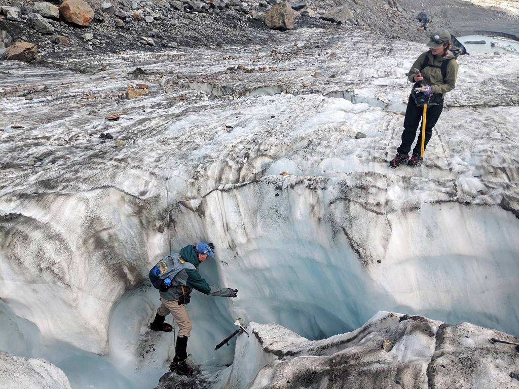 Scientist Mauri Pelto balances on the walls of an ice chute to take footage of a water current on <a href="https://www.heraldnet.com/news/chronicling-the-last-years-of-a-dying-north-cascades-glacier/" target="_blank">Columbia Glacier</a>. (Zachariah Bryan / The Herald)
