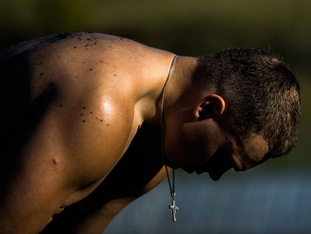 Monroe senior Gavin Monroes cross hangs as he stretches on the sidelines during practice. (Olivia Vanni / The Herald)