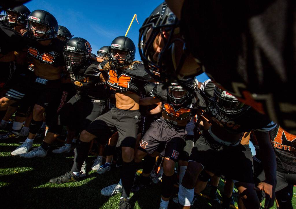 The Monroe High School football team gets together in a huddle before the start of football practice on Wednesday, Aug. 28, 2019 in Monroe, Wash. (Olivia Vanni / The Herald)