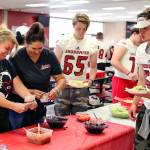 Jennifer Dodd (left) and Rachel Leggett work the taco table while James Justice and Liam Raney wait for the sour cream during the team meal before jamboree Friday afternoon at Snohomish High School. (Kevin Clark / The Herald)