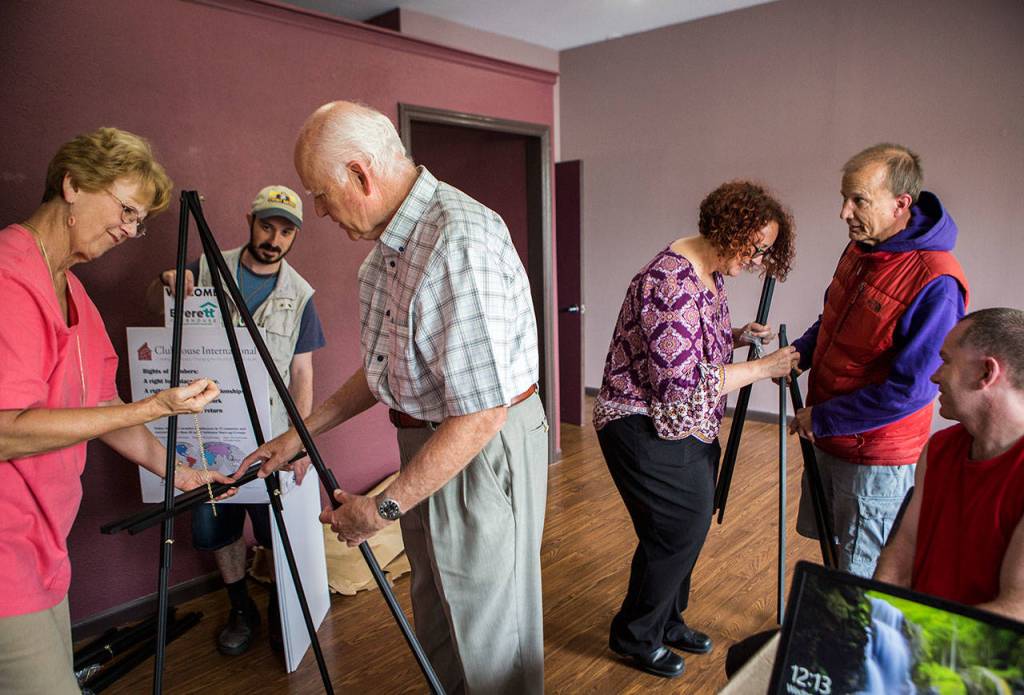 Clubhouse members Alex Odesskiy, Kaid Skirling and Chuck Johnson help set up poster board stands at the new Everett Clubhouse. (Olivia Vanni / The Herald)