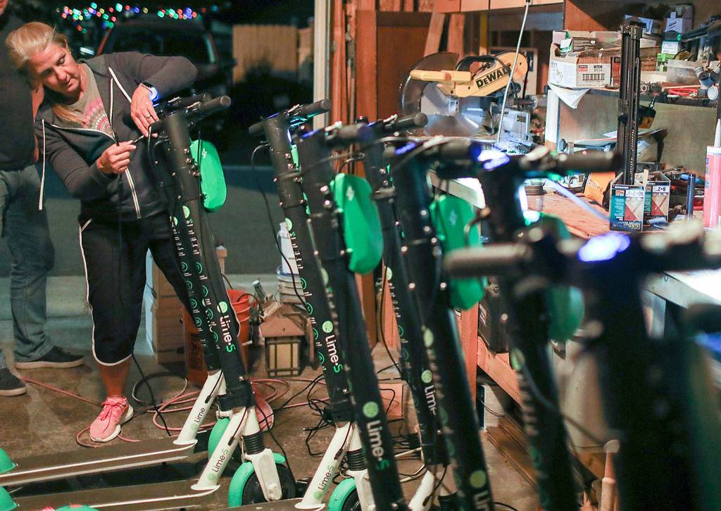 Lisa Baer plugs in the last scooter for the night. The Baers aimed to charge 12 e-scooters each night. (Lizz Giordano / The Herald)