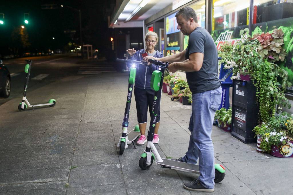 Lisa Baer, left, and Dan Baer unlock e-scooters before loading them into their car. (Lizz Giordano / The Herald)