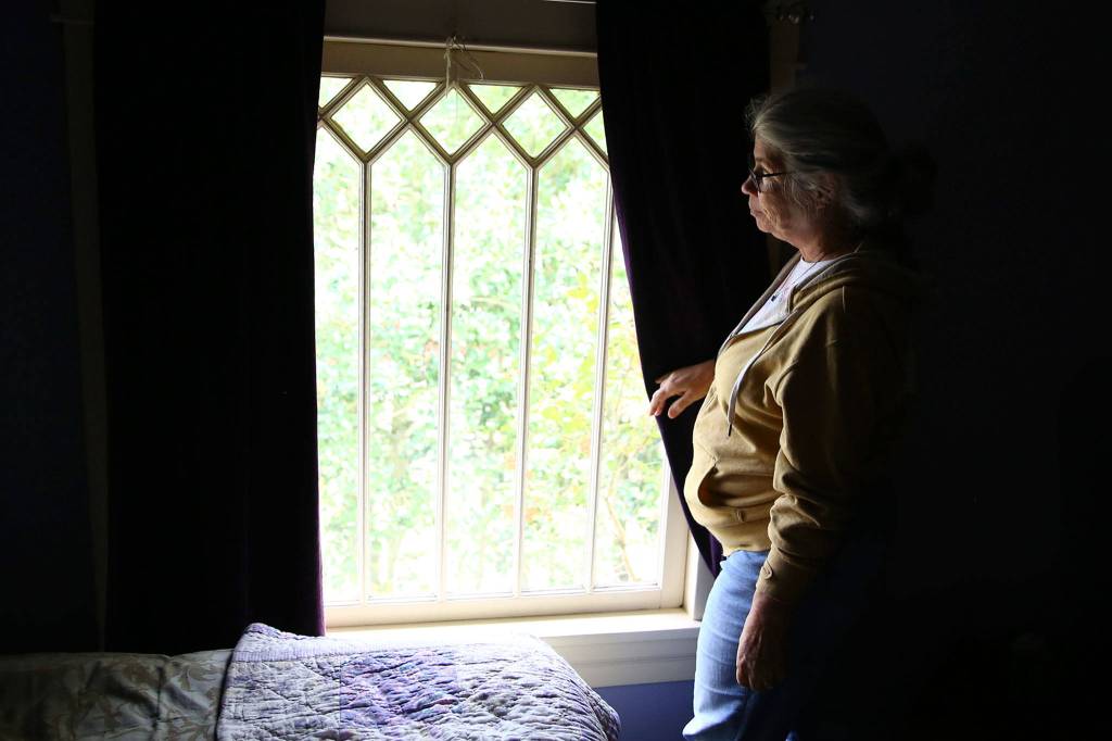 Susan Mausshardt looks out one of her homes many original windows, likely dating from when it was built in 1909. (Kevin Clark / The Herald)