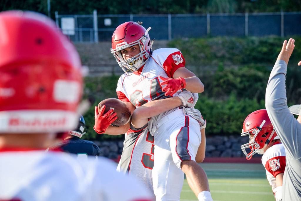 Junior defensive back Isaac Oretega is lifted up by his teammate after intercepting a Jackson pass in the second quarter on Friday at Everett Memorial Stadium. (Katie Webber / The Herald)