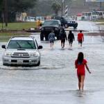 Residents walk and drive through the receding flood waters in Buxton, N.C., after Hurricane Dorian leaves Hatteras Island on Friday. (Steve Earley/The Virginian-Pilot via AP)