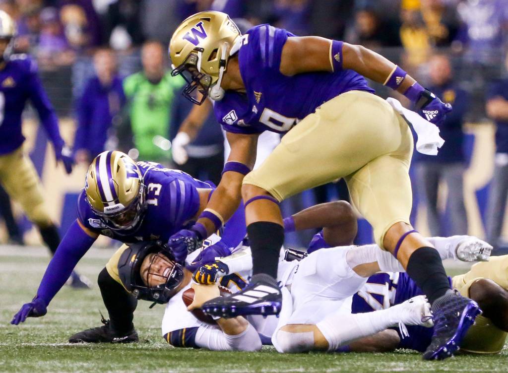 Californias Chase Garbers is sacked by Washingtons Brandon Wellington (left) and Joe Tryon Saturday night at Husky Stadium in Seattle on September 7, 2019.(Kevin Clark / The Herald)