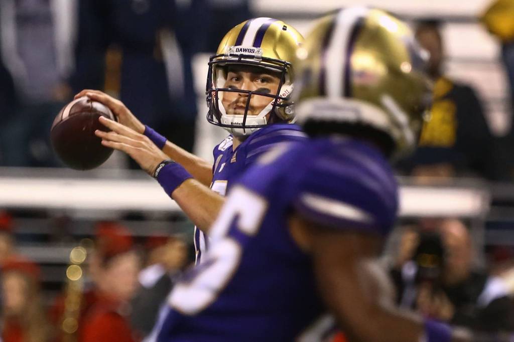 Washingtons Jacob Eason eyes teammate Salvon Ahmed for a pass against California Saturday night at Husky Stadium in Seattle on September 7, 2019.(Kevin Clark / The Herald)