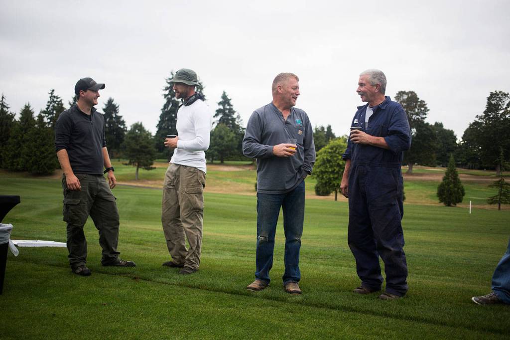 Members of Legion Memorial Golf Courses grounds crew talk before a dedication ceremony near the tee box on the 14th hole Wednesday in Everett. (Andy Bronson / The Herald)