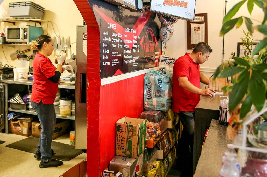 Deisy Ramos cooks in the back and her husband, Rigoberto Bastidak, takes orders at their restaurant, Taco-Book, in Everett. (Kevin Clark / The Herald)