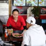 Deisy Ramos delivers food to customers at Taco-Book in Everett. (Kevin Clark / The Herald)