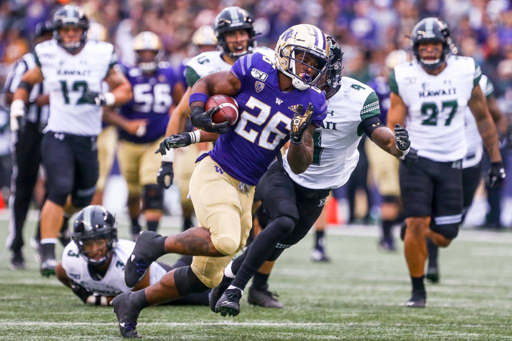Washingtons Salvon Ahmed races the Hawaii defenders Saturday evening at Husky Stadium in Seattle on September 14, 2019. Husky won 52-20. (Kevin Clark / The Herald)