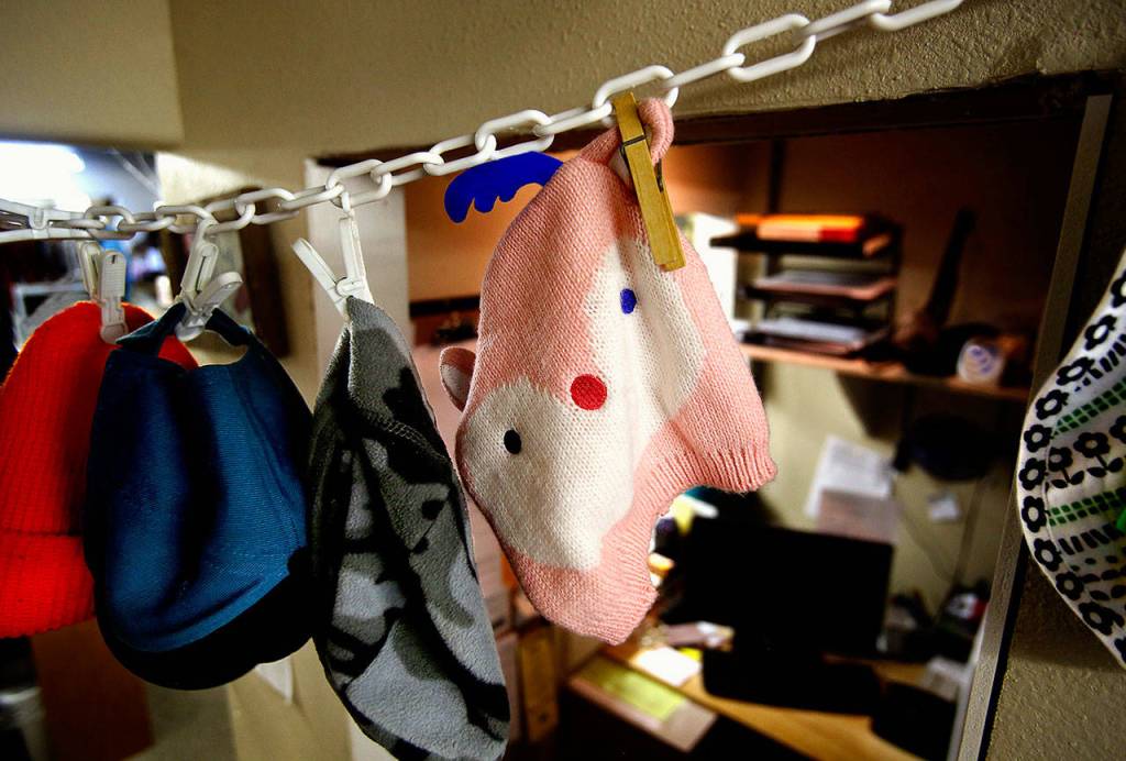 Displayed just outside the tiny business office at Saint Josephs House, a community clothing bank in Marysville are childrens winter caps, including a pink knitted hat with a red nose, blue eyes and blue antlers. (Dan Bates / The Herald)