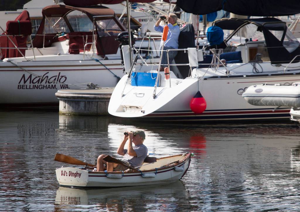 A pair of boaters watch the installation of the Grand Avenue Park Bridge as it is slowly rotated into place along Marine View Drive on Wednesday in Everett. (Andy Bronson / The Herald)