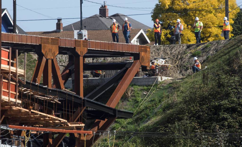 Crews watch as the east side of the Grand Avenue Park Bridge is lowered into place on Wednesday in Everett. (Andy Bronson / The Herald)