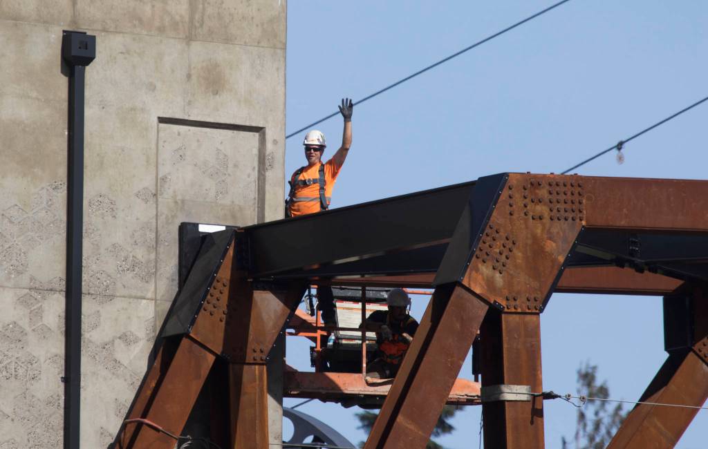 A worker waves to his mother as the Grand Avenue Park Bridge was lowered into place along Marine View Drive on Wednesday in Everett. (Andy Bronson / The Herald)