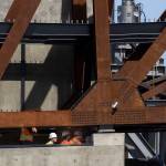 Workers watch from below as the $20 million Grand Avenue Park Bridge was slowly lowered into place above Marine View Drive on Wednesday in Everett. (Andy Bronson / The Herald)