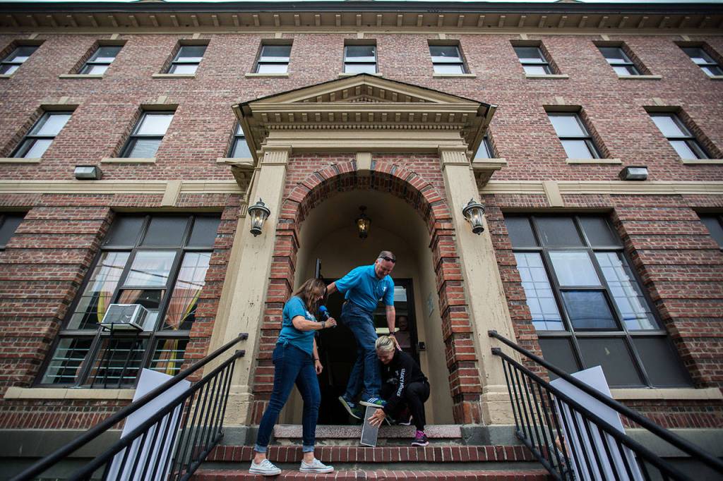 Snohomish County YMCA CEO Scott Washburn, center, stands on the new capsule as he tries to close it during the YMCAs time capsule ceremony on Saturday, Sept. 21, 2019 in Everett, Wash. (Olivia Vanni / The Herald)
