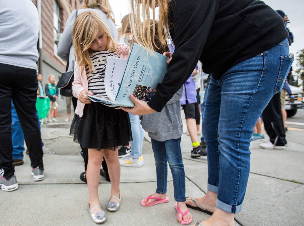 Harper Leslie, 5, flips through a The First 100 Years book on the Everett YMCA during the YMCAs time capsule ceremony on Saturday, Sept. 21, 2019 in Everett, Wash. (Olivia Vanni / The Herald)
