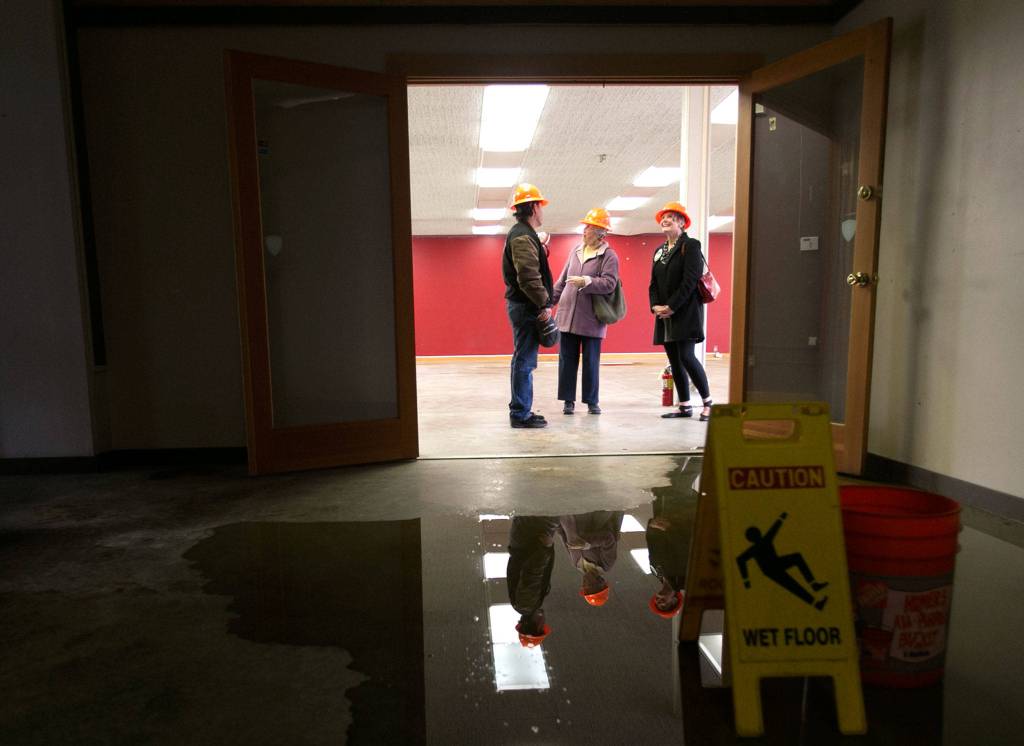 Mike Johnson shows Snohomish Carnegie Foundation members Melody Clemans and Terry Lippincott water damaged in the annex of the Snohomish Carnegie library in March 2018. (Kevin Clark / Herald file)