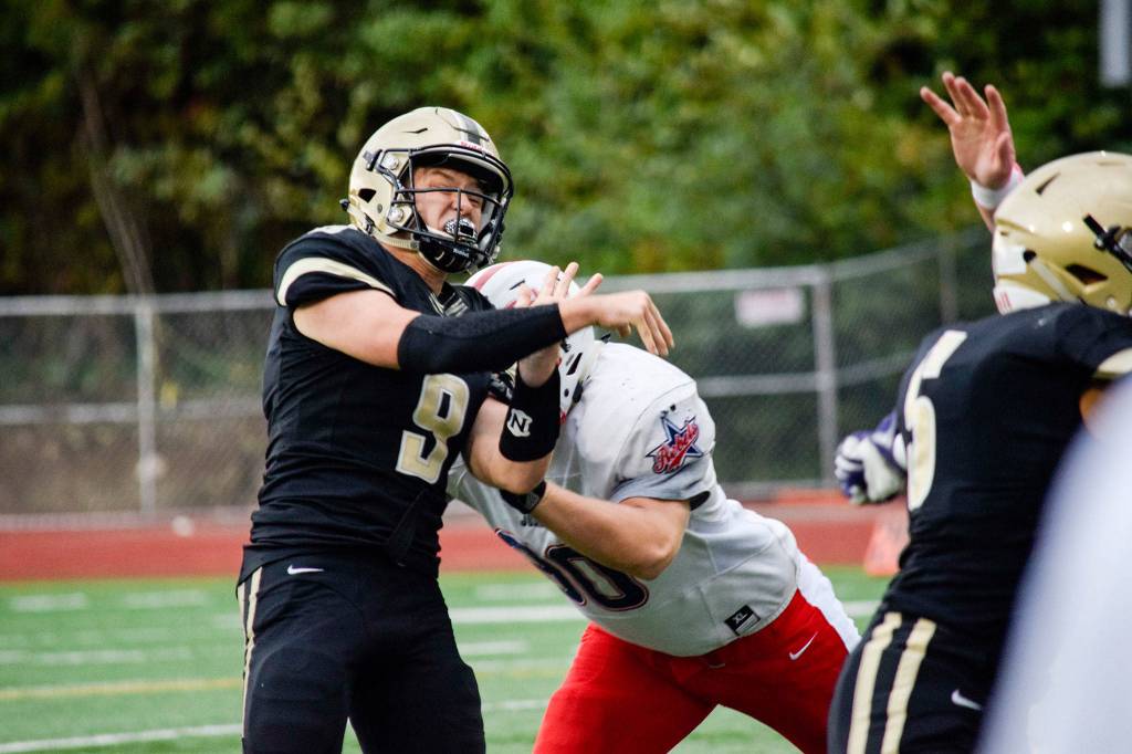 A Juanita defender hits Lynnwoods quarterback, Nate Killen, after throwing for a touchdown on Friday, Sept. 27 at Edmonds Stadium. (Katie Webber / The Herald)