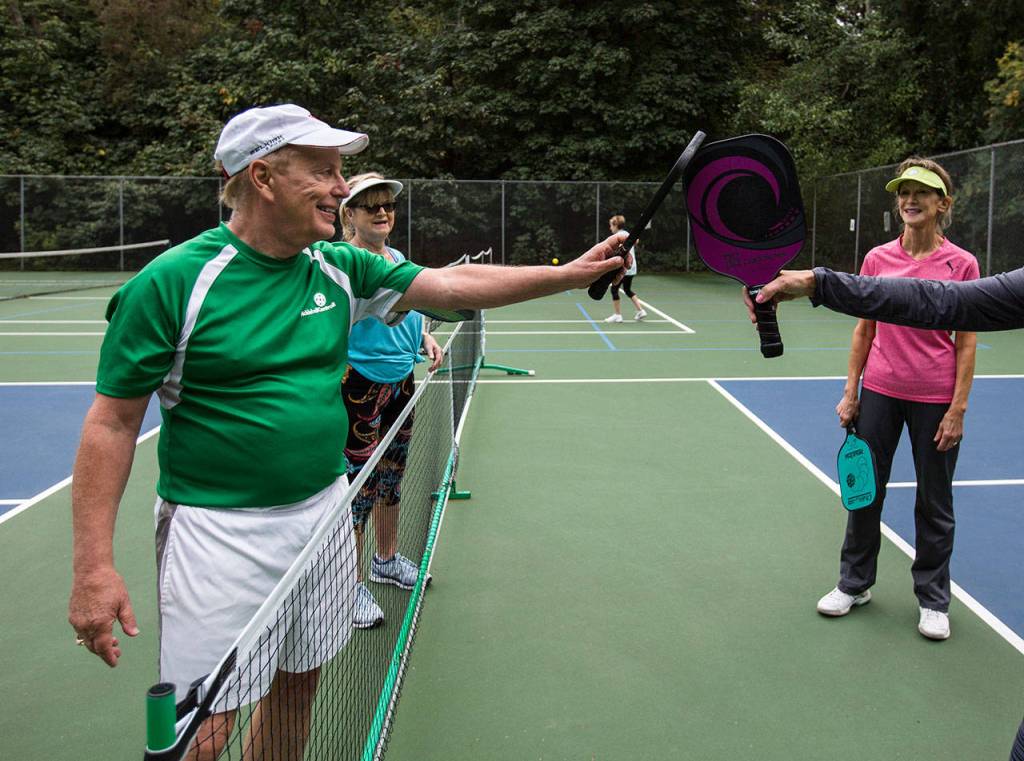 Roger BelAir touches pickleball paddles after a game at Yost Park. (Olivia Vanni / The Herald)
