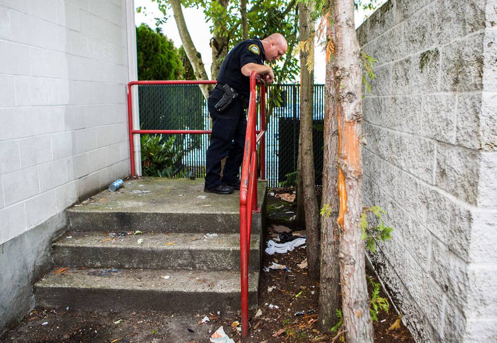 Officer Justin Springer checks for drug paraphanlia left behind at a site known to be frequented for drug use on Thursday in Monroe. (Olivia Vanni / The Herald)