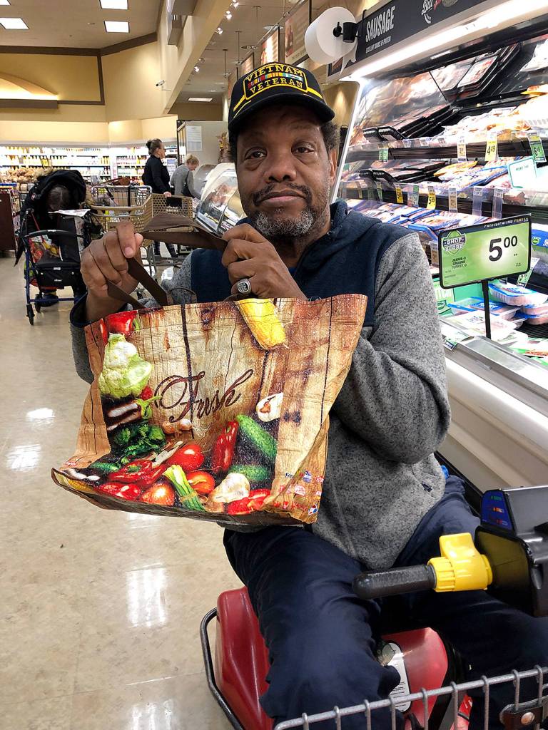 Albert Mojo Muldrow carries a fruit and veggie bag to an Everett store. (Janice Podsada / The Herald)