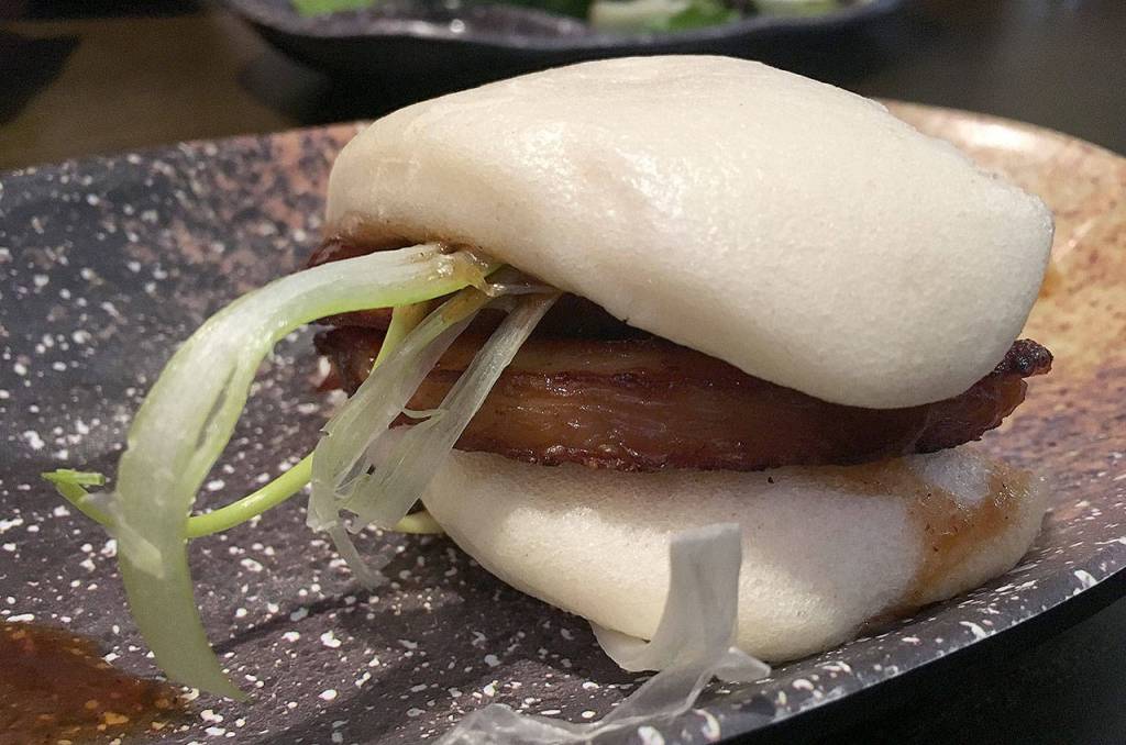 Pork belly buns can make for a light lunch with the doughy bun wrapped around a thick slice of pork belly at Botan Ramen n Bar in Everett. (Ben Watanabe / The Herald)