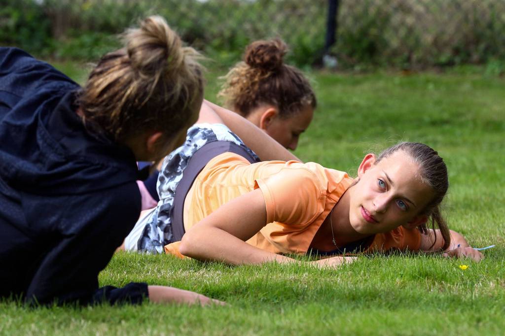 Glacier Peaks Madeline Watkins talks with teammates while stretching before running on Oct. 2, 2019, at Lord Hill Regional Park in Snohomish. (Kevin Clark / The Herald)