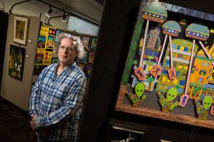 Artist Jerry Steffen Jr. at home and the Mountlake Terrace Public Library on Thursday, Oct. 3, 2019 in Mountlake Terrace, Wash. Steffen, who is Deaf, took first place in the Paintings Prints and Drawings category at the 2019 Arts of the Terrace for his paper cutouts. Two pieces, one entitled Kids Silly Face behind him and Taken Earth, right are on display with a third one, at the Library. (Andy Bronson / The Herald)