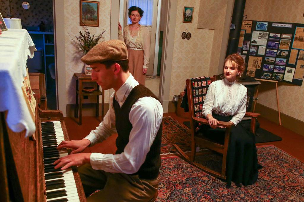 Edmundo Olanu, Autumn Adams and Emerald Adams reenact a typical evening in the parlor at the Grimm House. (Kevin Clark / The Herald)